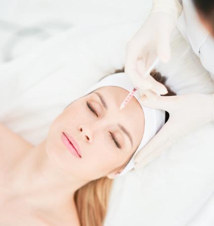 Botox injection on a woman's forehead at a dermatology clinic to reduce wrinkles and fine lines for a youthful look.