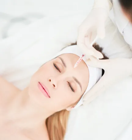 Botox injection on a woman's forehead at a dermatology clinic to reduce wrinkles and fine lines for a youthful look.