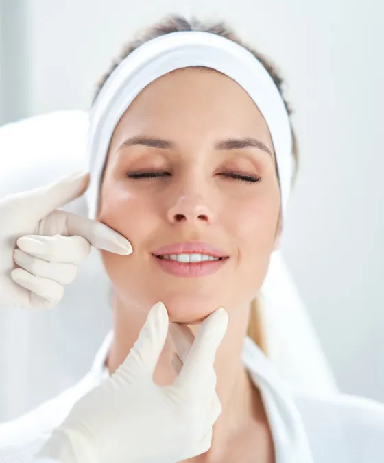 Dermatologist examining a woman's skin at a clinic for a personalized skincare treatment and facial rejuvenation.
