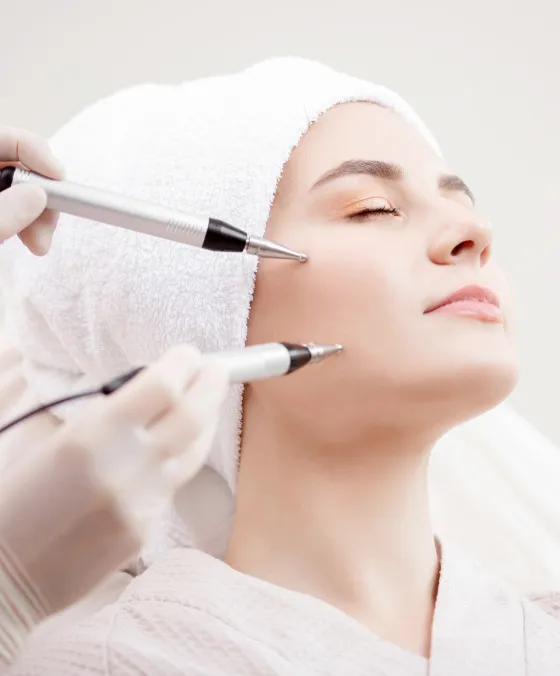 Woman receiving non-invasive microcurrent facial therapy at a dermatology clinic for skin tightening and rejuvenation.